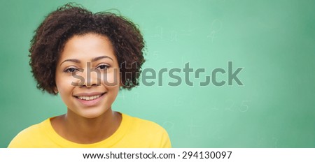people, race, ethnicity and portrait concept - happy african american young woman face over green chalk board background