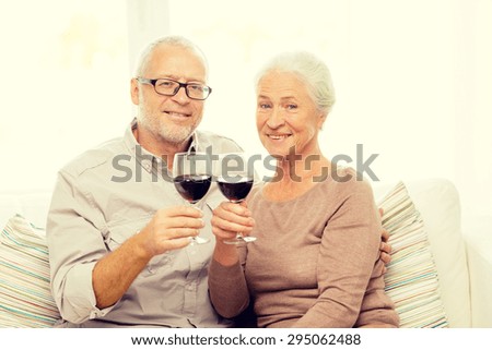 family, holidays, drinks, age and people concept - happy senior couple with glasses of red wine at home