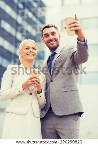 business, partnership, hot drinks and people concept - smiling businessmen with paper cups standing over office building