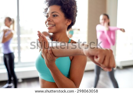 fitness, sport, dance, people  and lifestyle concept - close up of smiling african american woman with group of women dancing zumba in gym or studio