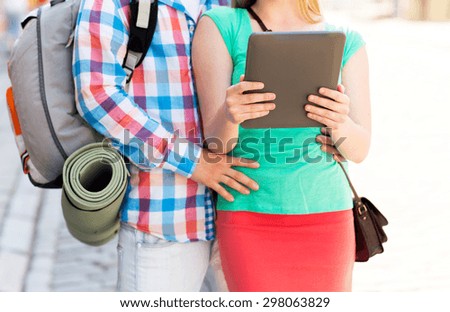 travel, tourism, technology and people concept - close up of couple with tablet pc and backpack in city