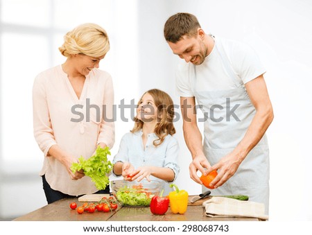 vegetarian food, culinary, happiness and people concept - happy family cooking vegetable salad for dinner over white room background