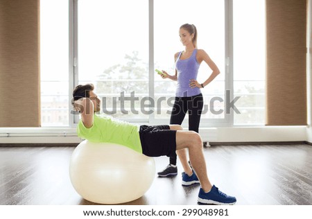 sport, fitness, lifestyle and people concept - smiling man and woman flexing muscles with exercise ball in gym