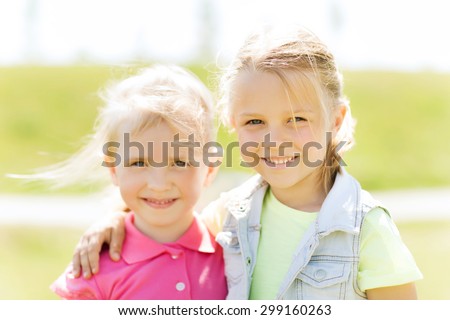 summer, childhood, leisure and people concept - happy little girls hugging outdoor