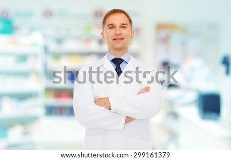 medicine, pharmacy, people, health care and pharmacology concept - smiling male pharmacist in white coat over drugstore background
