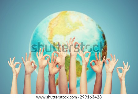 gesture, people, humanity and community concept - human hands showing ok sign over earth globe and blue background