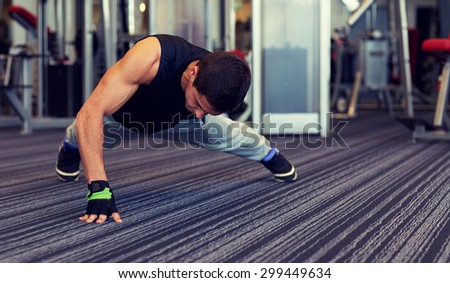 fitness, sport, people and lifestyle concept - man doing one arm push-ups in gym