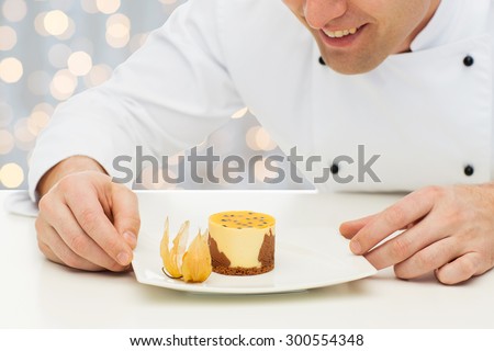 cooking, profession, haute cuisine, food and people concept - close up of happy male chef cook decorating dessert over holidays lights background