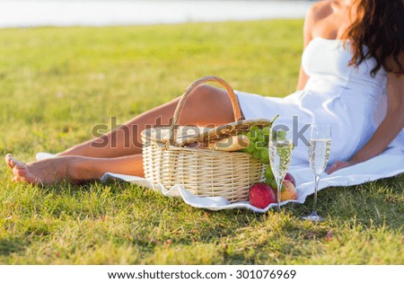 people, summer and holidays concept - close up of woman with food basket and champagne glasses on picnic