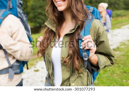 adventure, travel, tourism, hike and people concept - close up of happy woman and her friends hikers with backpacks walking on hiking trail