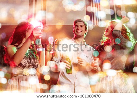 party, holidays, celebration, nightlife and people concept - smiling friends clinking glasses of champagne and beer in club