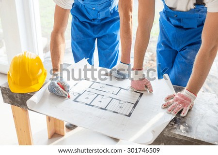 building, renovation, repair, teamwork and people concept - close up of builders discussing blueprint indoors