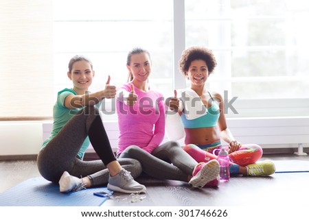 fitness, sport, training, gym and lifestyle concept - group of happy women with bottles of water showing thumbs up in gym