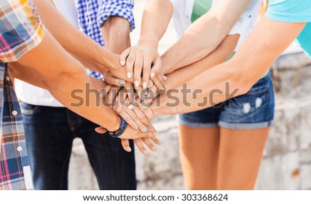 success, people, teamwork and gesture concept - cclose up of friends hands on top of each other outdoors