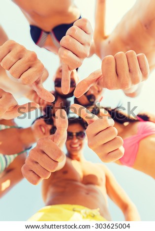 friendship, summer vacation, holidays, gesture and people concept - close up of smiling friends wearing swimwear standing in circle and showing thumbs up over blue sky
