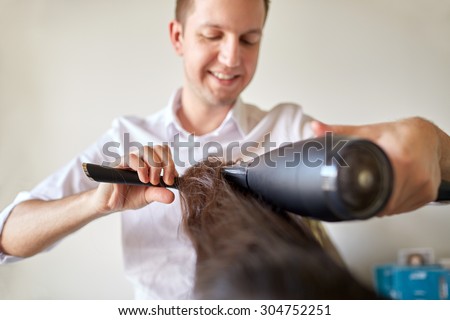 beauty, hairstyle, blow-dry and people concept - close up of hairdresser with hair dryer and brush making hot styling at salon