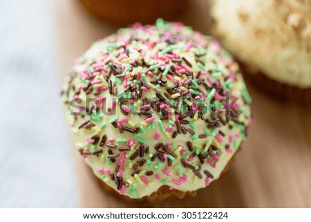 food, junk-food, culinary, baking and eating concept - close up of glazed cupcake or muffin on table