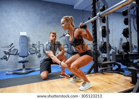 sport, fitness, teamwork, bodybuilding and people concept - young woman and personal trainer with bar flexing muscles in gym