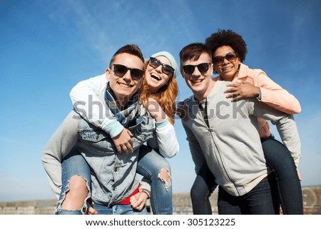 friendship, leisure, international and people concept - group of happy teenage friends in sunglasses having fun outdoors