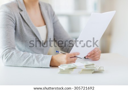 business, finance, tax and people concept - close up of woman hands with us dollar money and tax report paper form