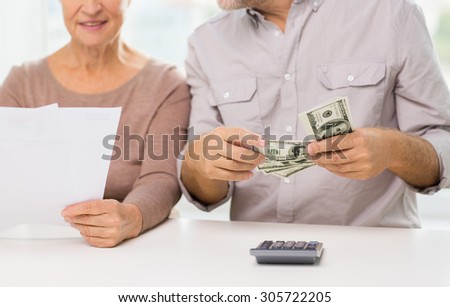 family, business, savings age and people concept - close up of smiling senior couple with bills, dollar money and calculator at home