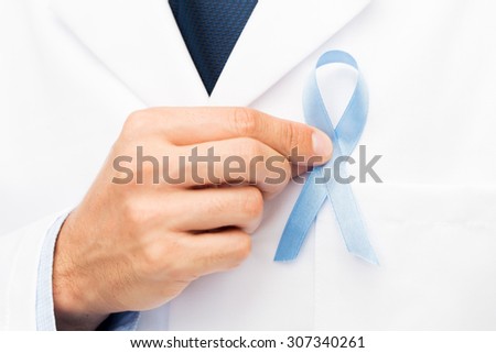 healthcare, profession, people and medicine concept - close up of male doctor hand with sky blue prostate cancer awareness ribbon