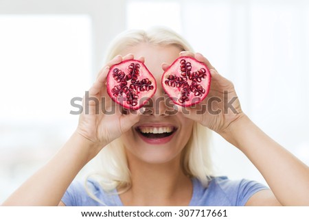 healthy eating, organic food, fruit diet, comic and people concept - happy woman having fun and covering her eyes with pomegranate