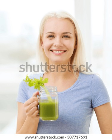 healthy eating, vegetarian food, dieting, detox and people concept - smiling woman drinking green vegetable juice or shake from glass at home
