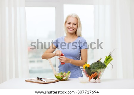 healthy eating, vegetarian food, dieting and people concept - smiling young woman cooking vegetable salad at home