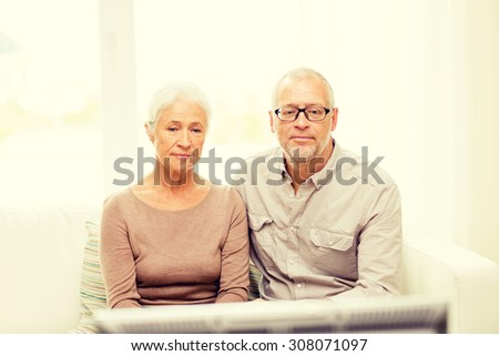 family, technology, age and people concept - senior couple watching tv at home
