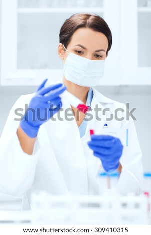 science, chemistry, biology, medicine and people concept - close up of young female scientist with test tube and pipette making research in clinical laboratory