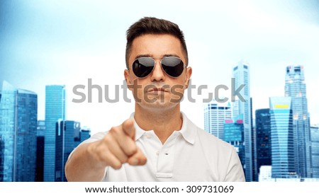 summer, accessories, style, gesture and people concept - face of middle aged latin man in white polo t-shirt and sunglasses pointing finger on you over city background