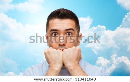 fear, horror, emotions and people concept - scared man face over blue sky and clouds background