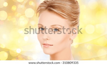beauty, people, holidays and health concept - beautiful young woman face over yellow lights background