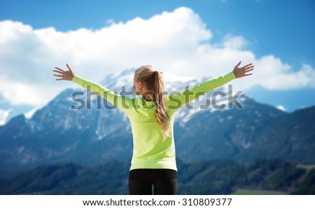 fitness, sport, peope and emotions concept - happy woman in sportswear enjoying sun and freedom over mountains and blue sky background from back