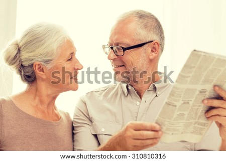 family, holidays, age and people concept - happy senior couple reading newspaper at home