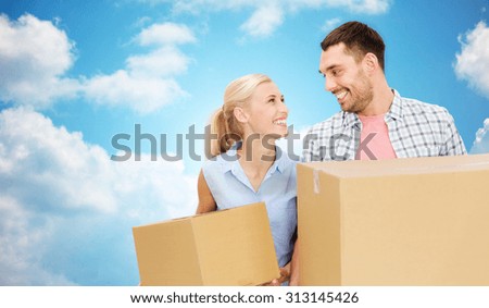 home, people, delivery and real estate concept - happy couple holding cardboard boxes over blue sky and clouds background