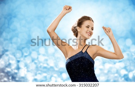 people, party, holidays and glamour concept - smiling woman dancing with raised hands over blue lights background