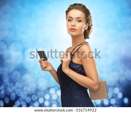 people, luxury, night life and finance concept - beautiful woman in evening dress with vip card and bag over blue lights background