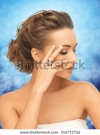people, jewelry, luxury and glamour concept - woman in white dress wearing diamond ring over blue lights background