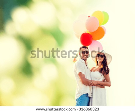 love, wedding, summer, dating and people concept - smiling couple wearing sunglasses with balloons hugging over green background
