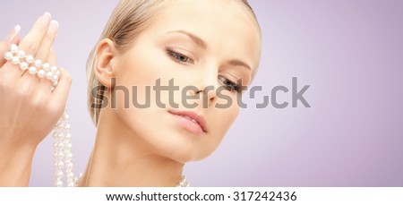 beauty, luxury, people, advertisement and jewelry concept - beautiful woman with sea pearl necklace or beads in hand over violet background