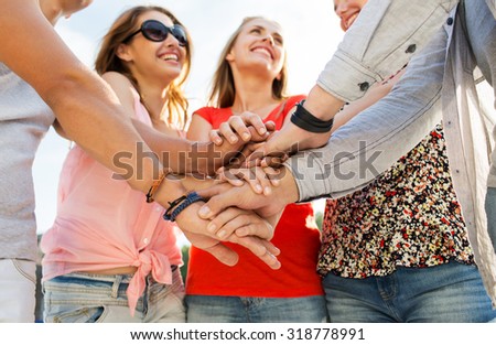 success, people, teamwork and gesture concept - close up of happy  friends  with hands on top of each other outdoors