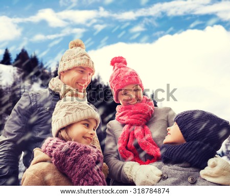 family, childhood, season and people concept - happy family in winter clothes over snowy mountains background