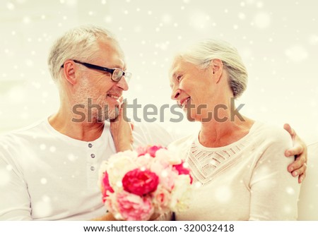 family, holidays, age and people concept - happy senior couple with bunch of flowers at home