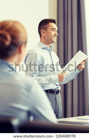 business, people and teamwork concept - smiling businessman holding papers and woman on presentation in office