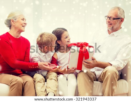 family, holidays, generation, christmas and people concept - smiling grandparents and grandchildren with gift box sitting on couch at home