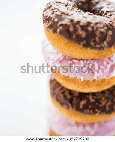 food, junk-food and eating concept - close up of glazed donuts pile over white