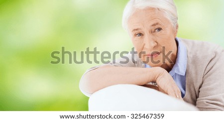 age and people concept - happy smiling senior woman face over green natural background