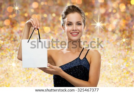 shopping, luxury, advertisement, people and sale concept - smiling woman with white blank shopping bag over golden holydays lights background